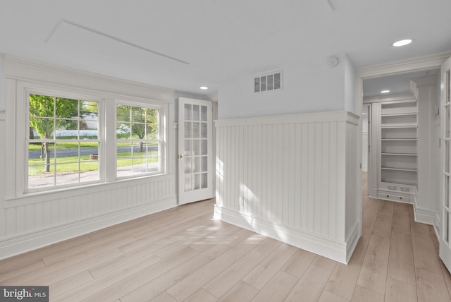 spare room featuring visible vents, light wood finished floors, and wainscoting