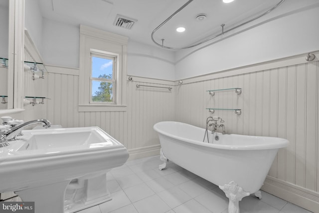 bathroom with tile patterned flooring, visible vents, a freestanding bath, a wainscoted wall, and a sink