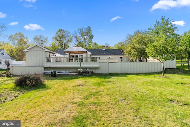 rear view of property with fence, a deck, a gazebo, board and batten siding, and a lawn