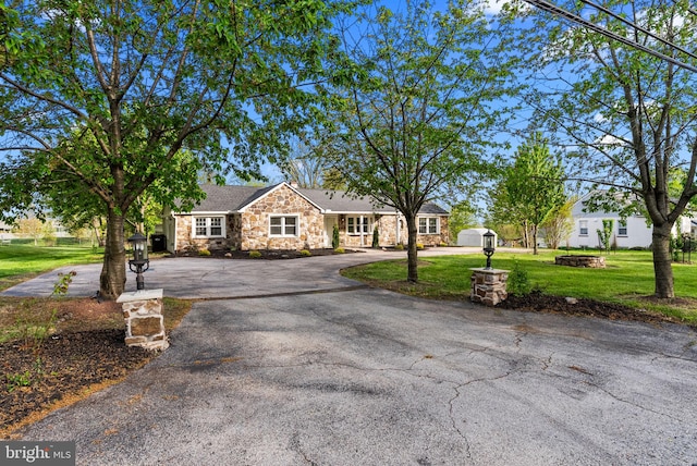 ranch-style house with curved driveway, a front yard, and stone siding