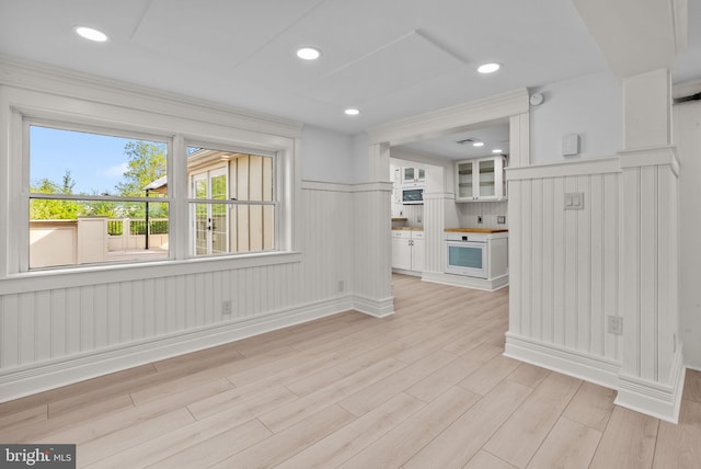 unfurnished living room featuring recessed lighting, light wood-style flooring, and wainscoting