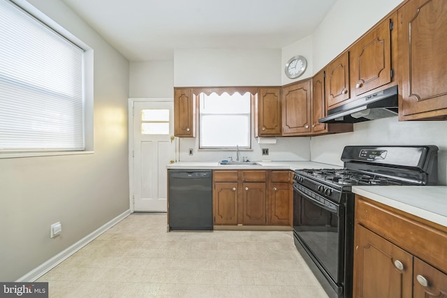 2426 S Chadwick St, Philadelphia, PA 19145 - kitchen featuring brown cabinetry, light countertops, under cabinet range hood, a sink, and black appliances