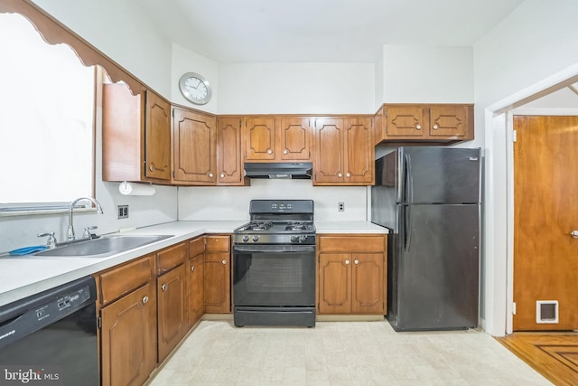 2426 S Chadwick St, Philadelphia, PA 19145 - kitchen featuring brown cabinetry, a sink, light countertops, black appliances, and under cabinet range hood
