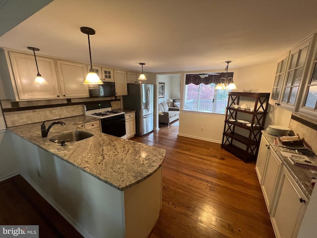 kitchen with black microwave, light stone countertops, gas stove, a sink, and stainless steel fridge