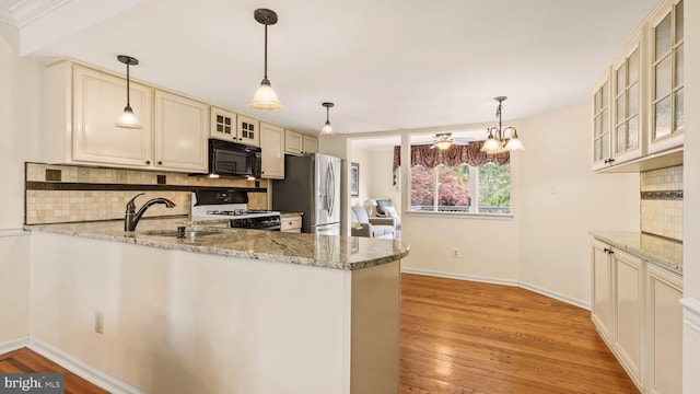 kitchen with black microwave, stainless steel fridge, a sink, white gas stove, and decorative backsplash