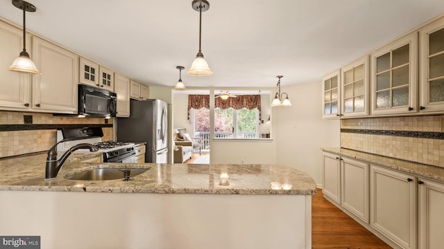 kitchen with wood finished floors, black microwave, white range with gas cooktop, cream cabinets, and backsplash