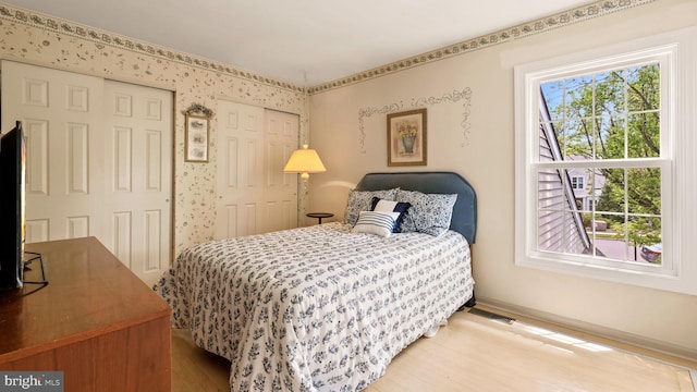 bedroom featuring baseboards, wood finished floors, and visible vents