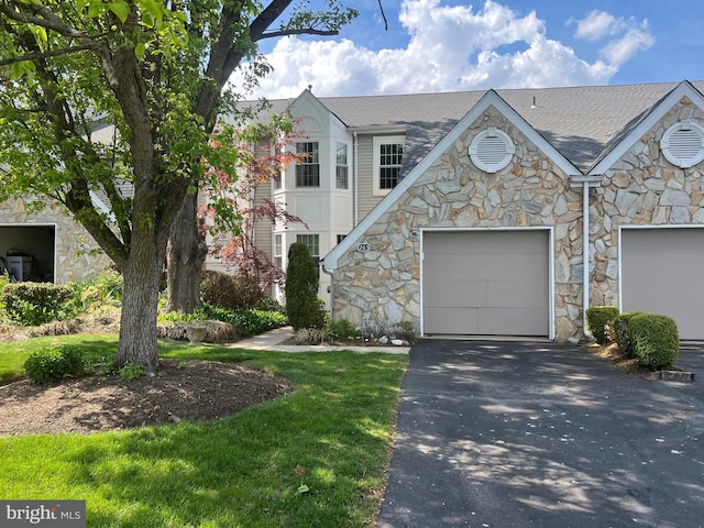view of front of home featuring a garage, a shingled roof, aphalt driveway, and stone siding