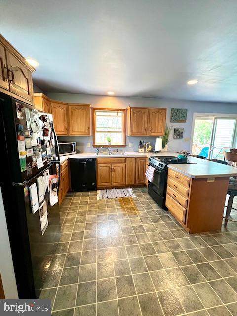 kitchen with light countertops, black appliances, a peninsula, and a wealth of natural light