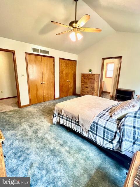 carpeted bedroom featuring two closets, a ceiling fan, baseboards, vaulted ceiling, and visible vents