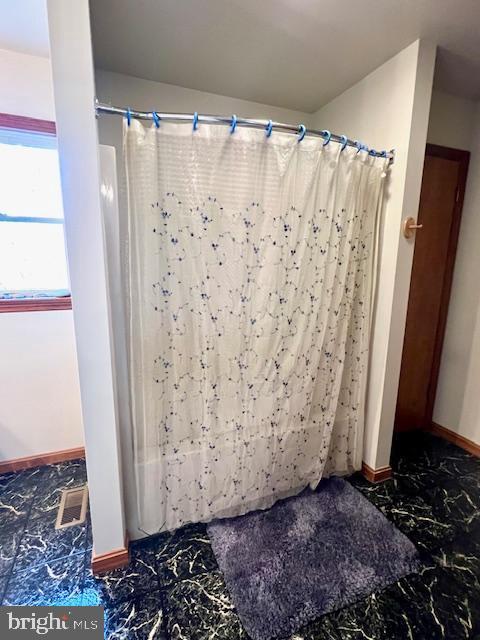 bathroom with baseboards, marble finish floor, visible vents, and a shower with curtain