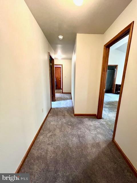 hallway featuring carpet flooring and baseboards