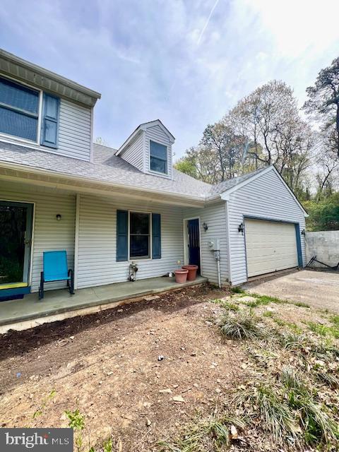 view of front of home with a garage, covered porch, driveway, and roof with shingles