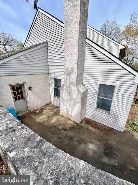 view of side of property featuring a patio and a chimney