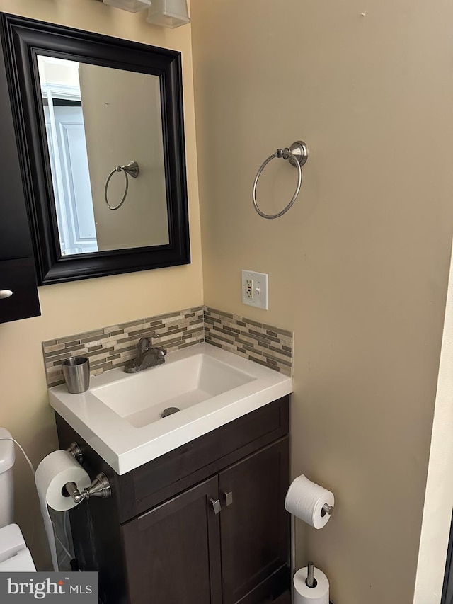 half bathroom featuring toilet, decorative backsplash, and vanity