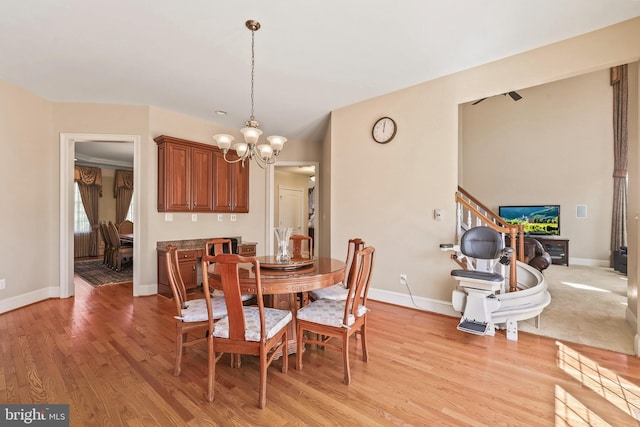 dining area with baseboards, an inviting chandelier, and light wood finished floors