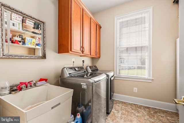 clothes washing area with baseboards, a sink, cabinet space, and washing machine and clothes dryer