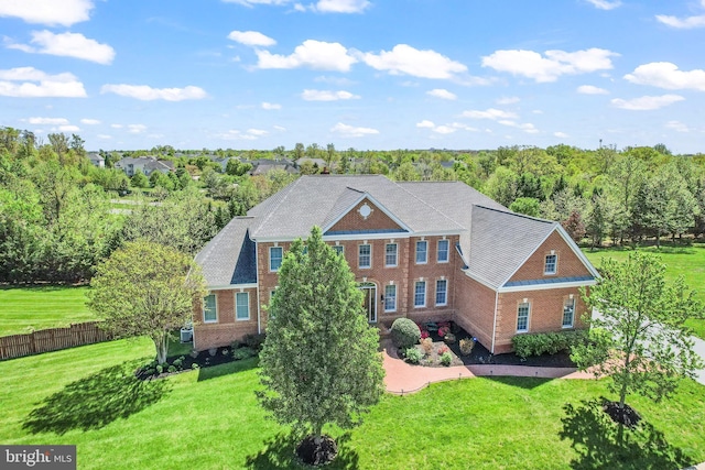 georgian-style home featuring brick siding, fence, and a front yard