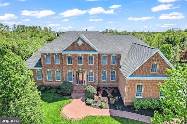 colonial house with brick siding, a front lawn, and a standing seam roof