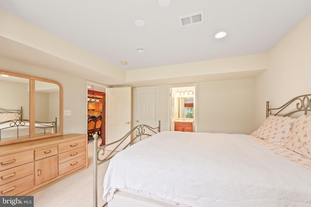 bedroom with visible vents, recessed lighting, ensuite bath, and light carpet