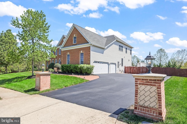 43112 Unison Knoll Cir, Ashburn, VA 20148 - view of property exterior with aphalt driveway, fence, a lawn, brick siding, and an attached garage