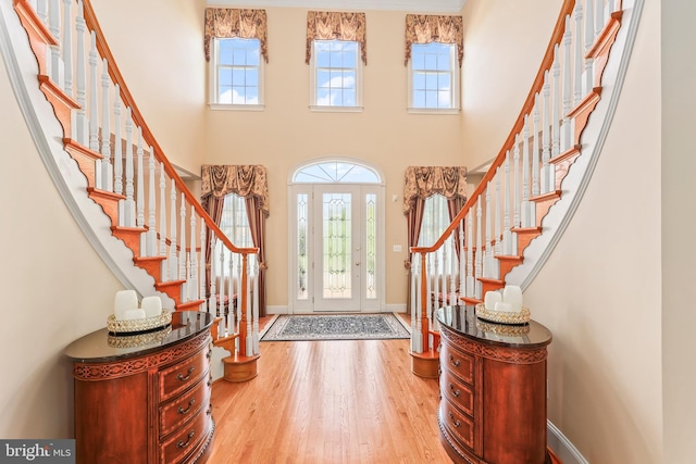 foyer with stairs, baseboards, wood finished floors, and a towering ceiling