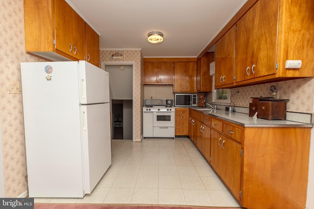 kitchen featuring brown cabinetry, a sink, white appliances, and wallpapered walls