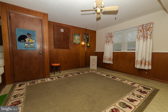 interior space featuring ceiling fan and wood walls