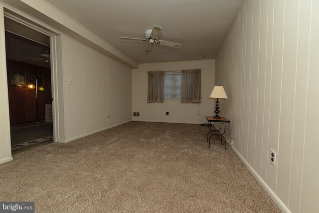 carpeted empty room featuring baseboards, a ceiling fan, and visible vents