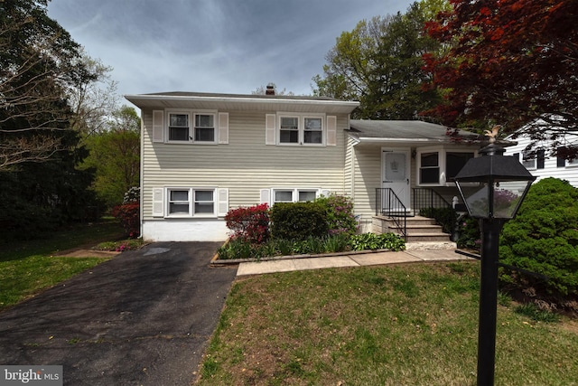 tri-level home featuring driveway and a front lawn