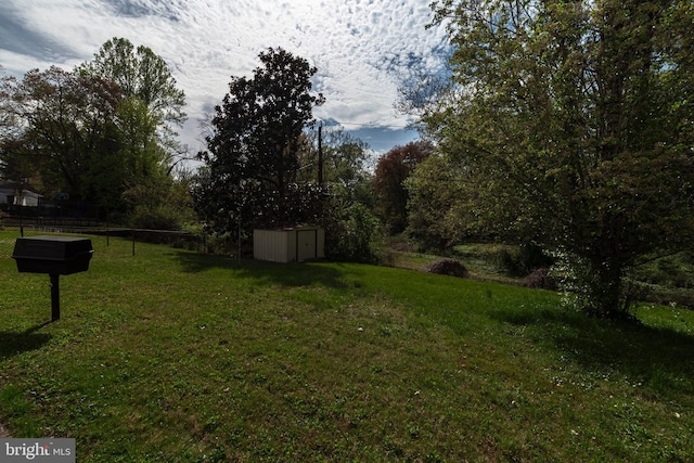 view of yard featuring an outdoor structure, fence, and a storage shed
