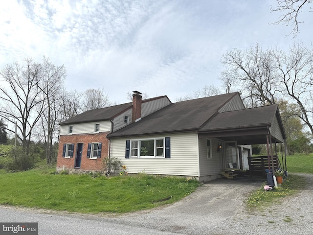 view of side of property with a chimney, roof with shingles, a lawn, a carport, and aphalt driveway
