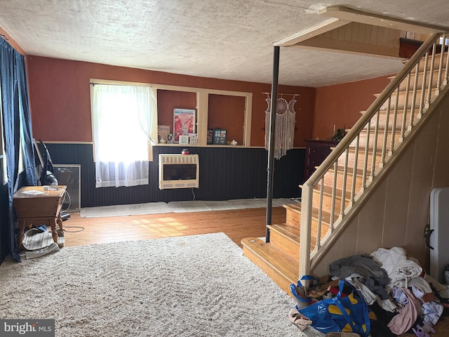 interior space with heating unit, a textured ceiling, stairs, and wood finished floors