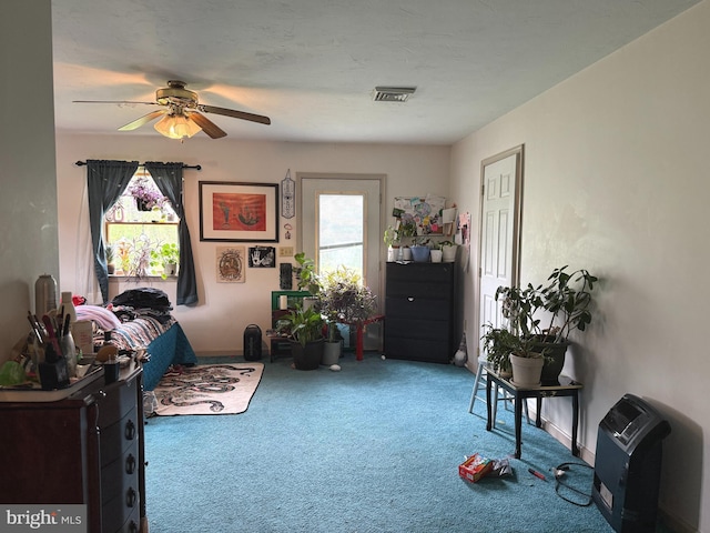 sitting room featuring visible vents, carpet flooring, ceiling fan, and a wealth of natural light