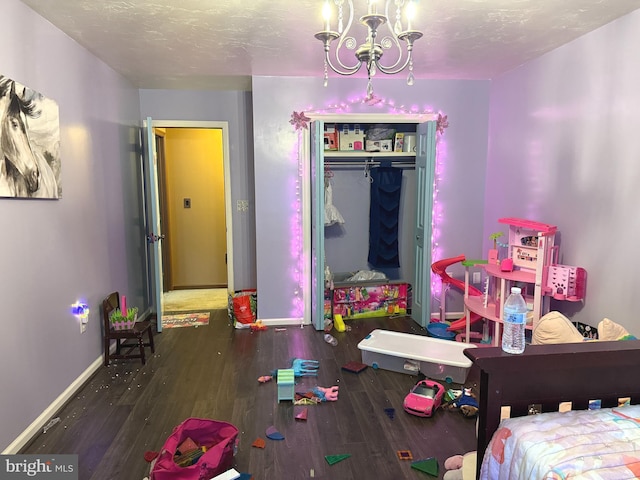 bedroom featuring baseboards, wood finished floors, a chandelier, and a closet
