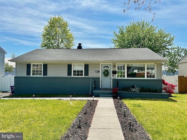 view of front of home with brick siding, a shingled roof, fence, and a front yard