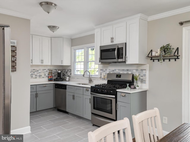 kitchen with light countertops, gray cabinets, tasteful backsplash, a sink, and stainless steel appliances