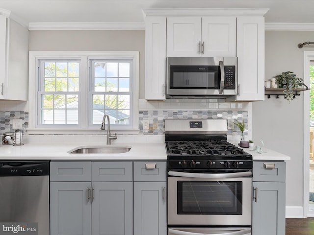 kitchen with a sink, appliances with stainless steel finishes, crown molding, and light countertops