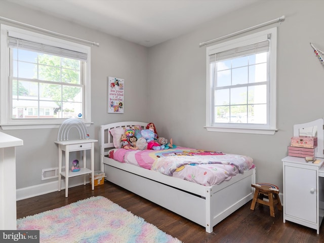bedroom with baseboards, wood finished floors, and multiple windows