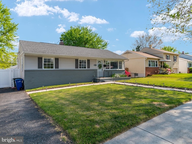 single story home featuring brick siding, fence, a chimney, and a front yard