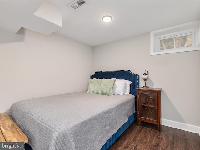bedroom with baseboards, visible vents, and wood finished floors