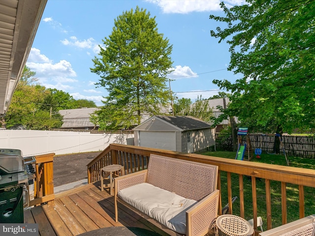 wooden deck with a grill, a fenced backyard, a yard, a playground, and an outbuilding