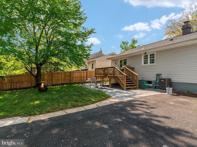 rear view of property featuring fence, a deck, a patio area, a lawn, and central air condition unit