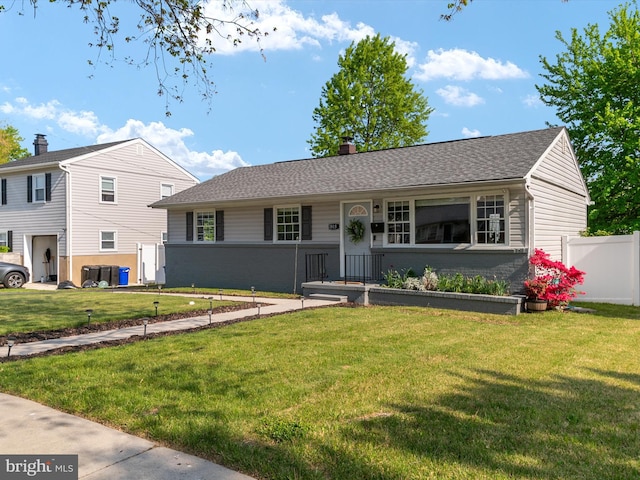 ranch-style home featuring a chimney, brick siding, fence, cooling unit, and a front lawn