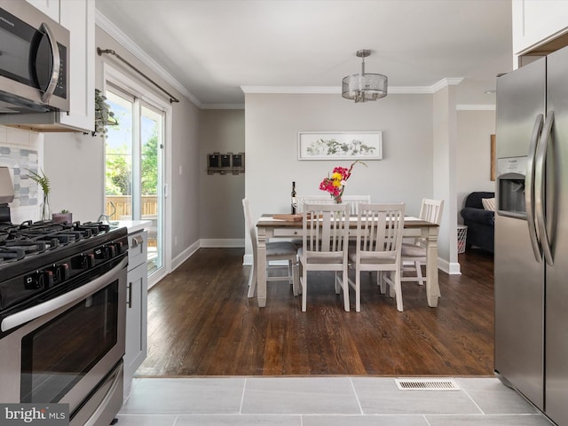 kitchen with visible vents, crown molding, appliances with stainless steel finishes, baseboards, and white cabinets
