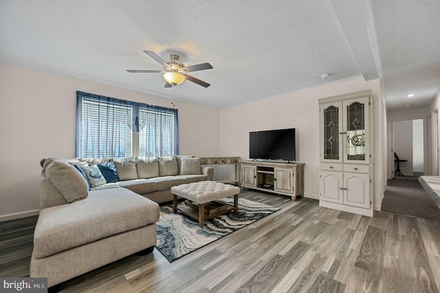 living area with baseboards, a textured ceiling, light wood-style flooring, and ceiling fan