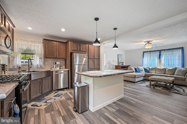 kitchen with a textured ceiling, a sink, light countertops, stainless steel appliances, and dark wood-type flooring