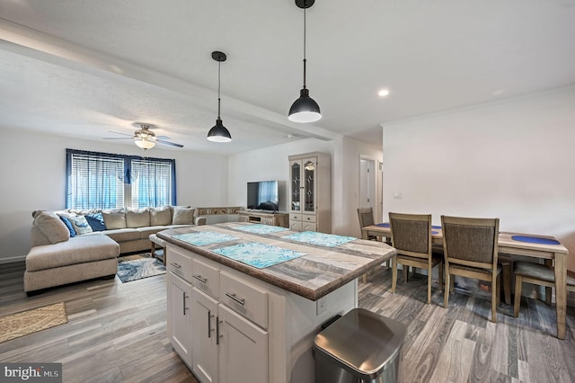 kitchen with a kitchen island, white cabinetry, open floor plan, and light wood-style floors