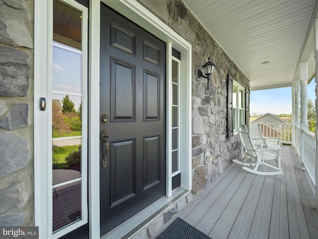 entrance to property featuring covered porch and stone siding