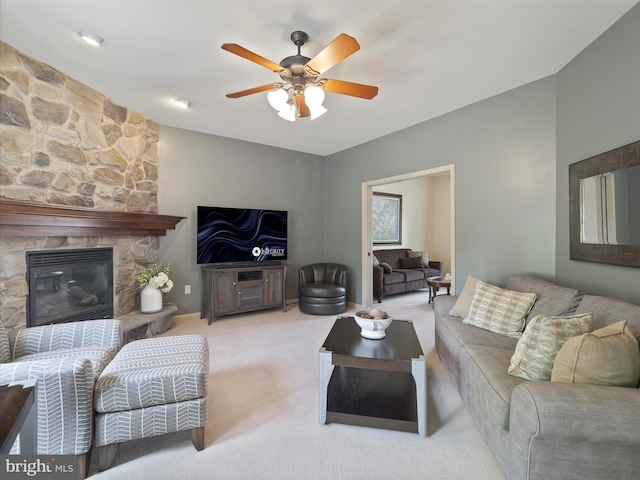 living room featuring ceiling fan, a stone fireplace, and carpet